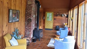 Un interior acogedor con paredes de madera, una chimenea de ladrillo y una zona de estar con sofá y sillones.