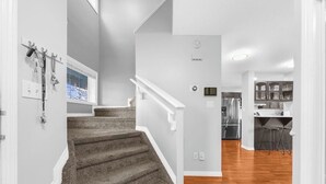 A staircase leading to a kitchen with a stainless steel refrigerator and bar stools.