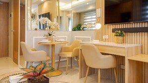 A modern, well-lit room with a dining area, a TV mounted on the wall, and a large mirror reflecting the space. - Sleek and Stylish 1br in Mall Of Asia Complex (Pasay)