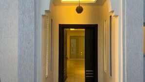 A hallway with a modern design, featuring a recessed ceiling and a central light fixture.