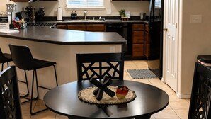 A kitchen with wooden cabinets, a central island, and a dining area with a table and chairs.