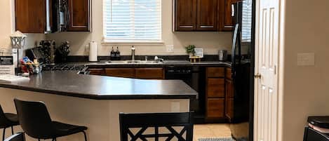 A kitchen with wooden cabinets, a central island, and a dining area with a table and chairs.