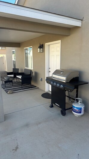 Eine Terrasse mit Grill, Stühlen und Gasflasche.