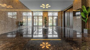 A modern lobby with a reflective marble floor, large windows, and a central plant display. - Holiday Inn Jiuhua Mountain Hot Spring by IHG (Chizhou)