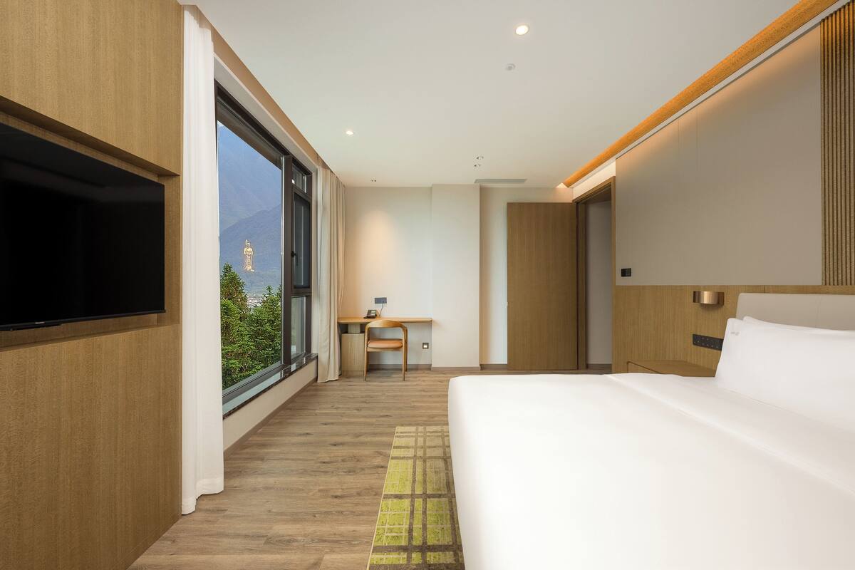 A modern hotel room with a large bed, a desk, and a TV.