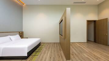 A modern hotel room with a large bed, a wooden floor, a wooden wardrobe, and a door leading to another room.