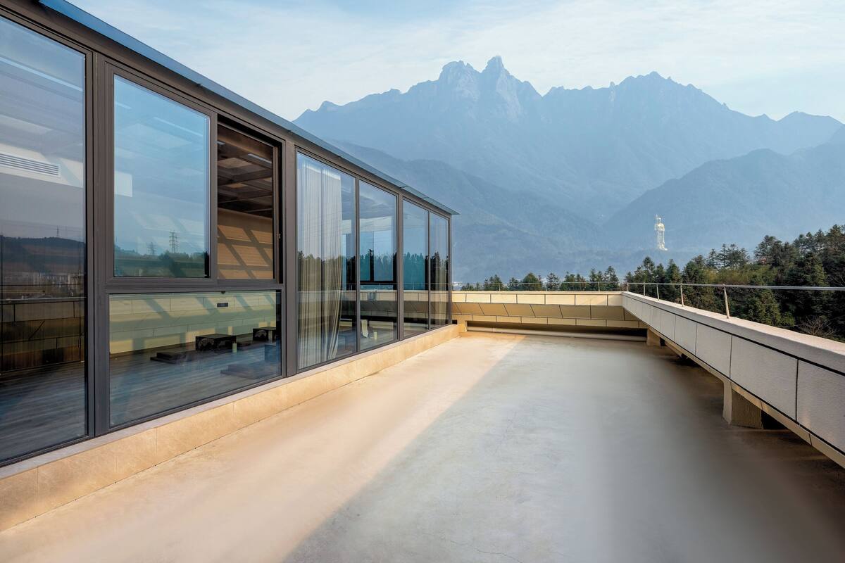 A modern building with large windows overlooking a mountainous landscape.