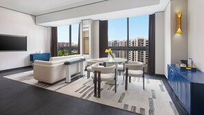 A modern living room with a sofa, chairs, a coffee table, and a TV. It features large windows with a city view. - voco Suites Shanghai Hongqiao CBD by IHG (Shanghai)