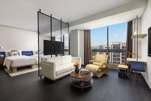 A modern hotel room with a bed, sofa, armchair, desk, and a large window offering a city view. - voco Suites Shanghai Hongqiao CBD by IHG (Shanghai)