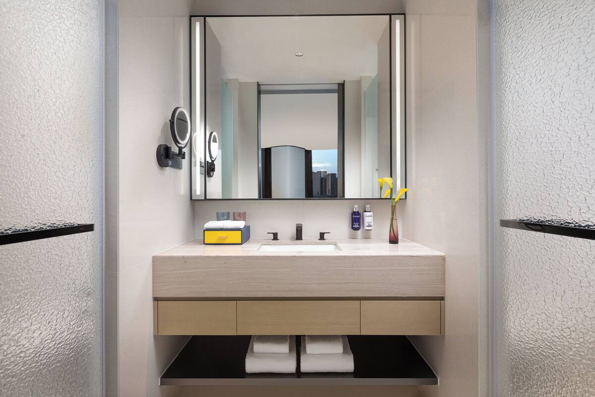 A modern bathroom with a large mirror, a sink, and a towel rack.