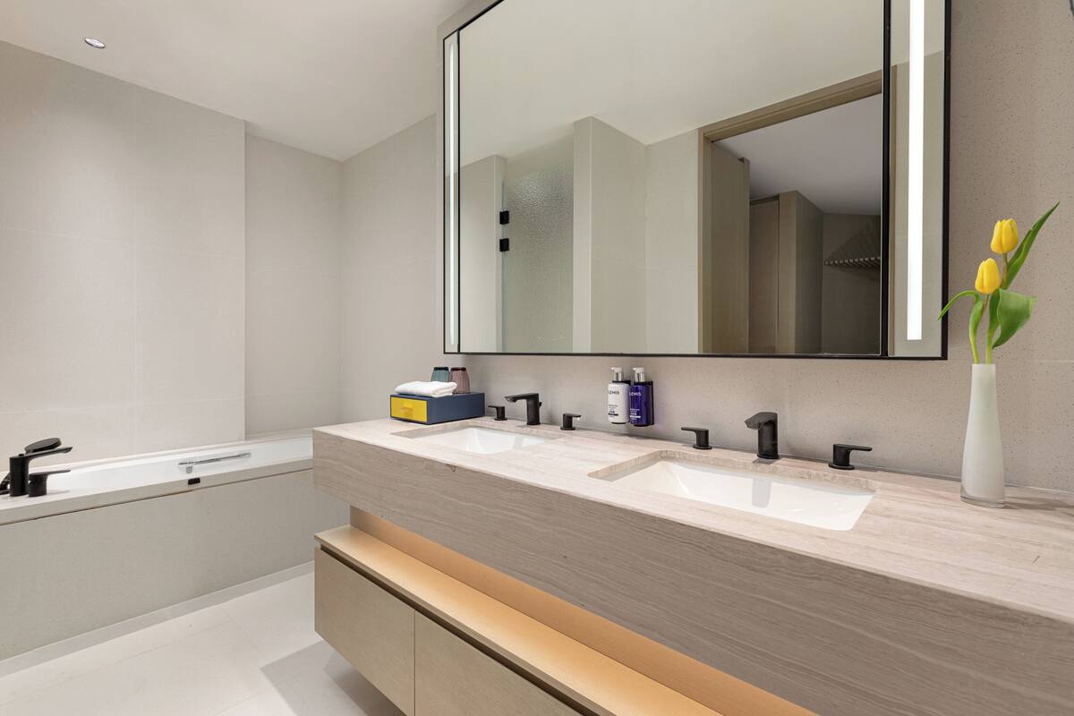 A modern bathroom with two sinks, a large mirror, and a wooden vanity.