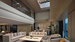 A spacious lobby with a high ceiling, a central seating area with sofas and armchairs, a coffee table, and a dining area with a table and chairs. - voco Suites Shanghai Hongqiao CBD by IHG (Shanghai)