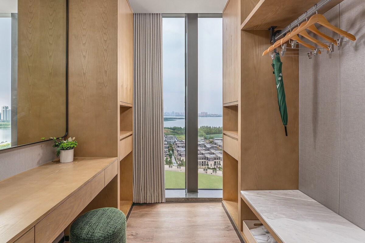 A modern bathroom with a large window, wooden vanity, and a green plant.