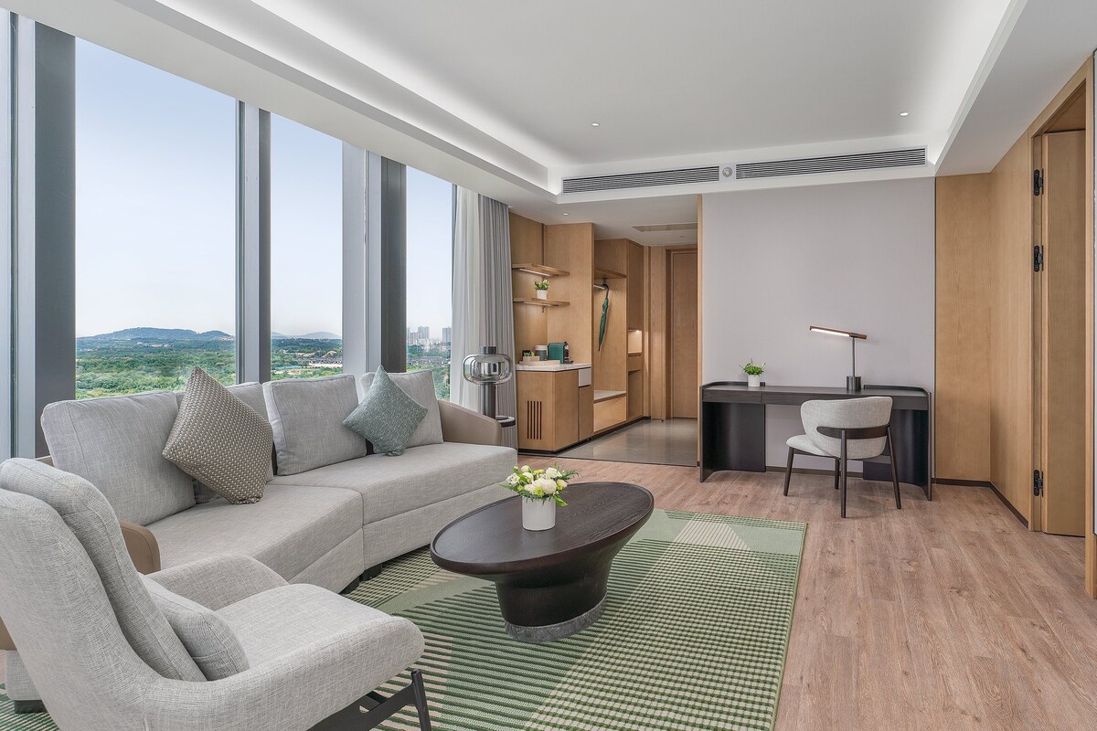 A modern living room with a sofa, coffee table, and a desk area.