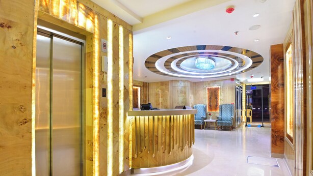 Et hotellets reception med et moderne design, der inkluderer en receptionsdisk, et loungeområde og en stor lysekrone.