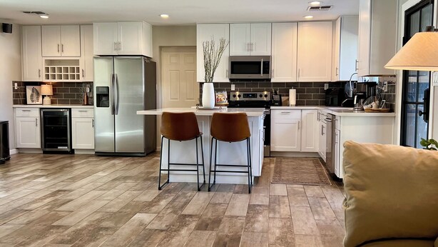 A modern kitchen with white cabinets, stainless steel appliances, and a central island with two stools. - Arcadia oasis Heated Pool (Phoenix)