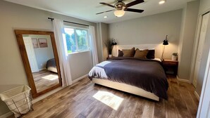 A bedroom with a bed, a ceiling fan, a window with curtains, a nightstand, and a plant. - Arcadia oasis Heated Pool (Phoenix)