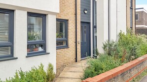 A row of modern terraced houses with brick and white facades, a concrete pathway, and a brick wall separating the properties. - St Mary's Sunscape (Huntingdon)