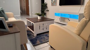 A living room with a sofa, a coffee table, a TV, and a cabinet with blue lighting. - Eagle Stay 13- Eagle Pass (Eagle Pass)