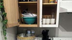 A kitchen with a microwave, stove, and various kitchen items on shelves. - Eagle Stay 13- Eagle Pass (Eagle Pass)