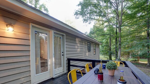 Une terrasse en bois avec une table, des chaises et un éclairage extérieur.