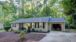 Une maison de plain-pied avec un porche à l’avant, un garage et une cour bien entretenue.