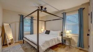 Un lit à baldaquin avec un ventilateur de plafond, une table de chevet avec une lampe et un grand miroir.