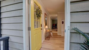 Un couloir avec une porte jaune, une lampe et une petite table avec une chaise.