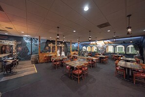 A restaurant with wooden tables and chairs, a mural on the wall, and hanging lights. - Studio 6 Pocatello, Id (Pocatello)