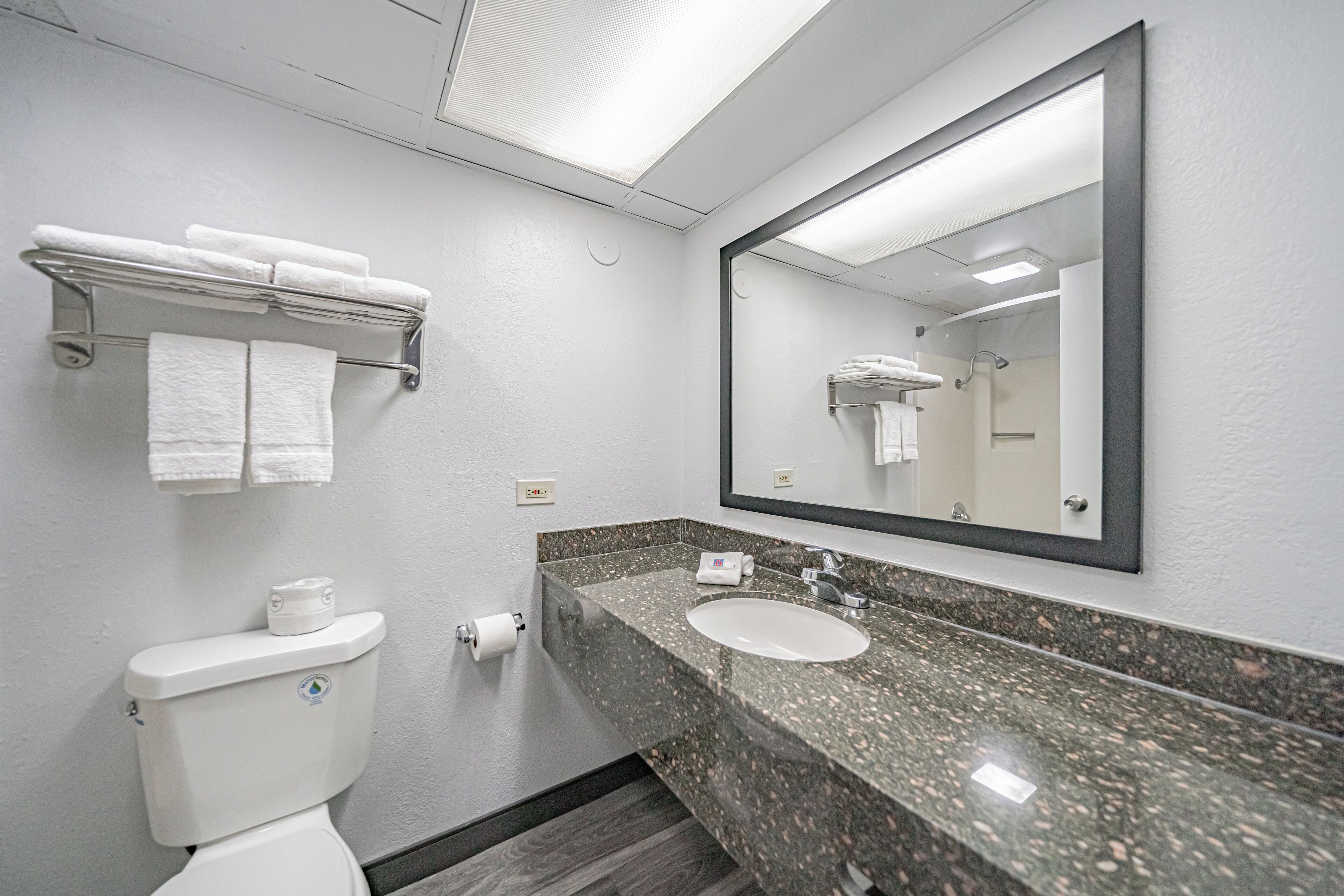 Een badkamer met toilet, wastafel en een grote spiegel.