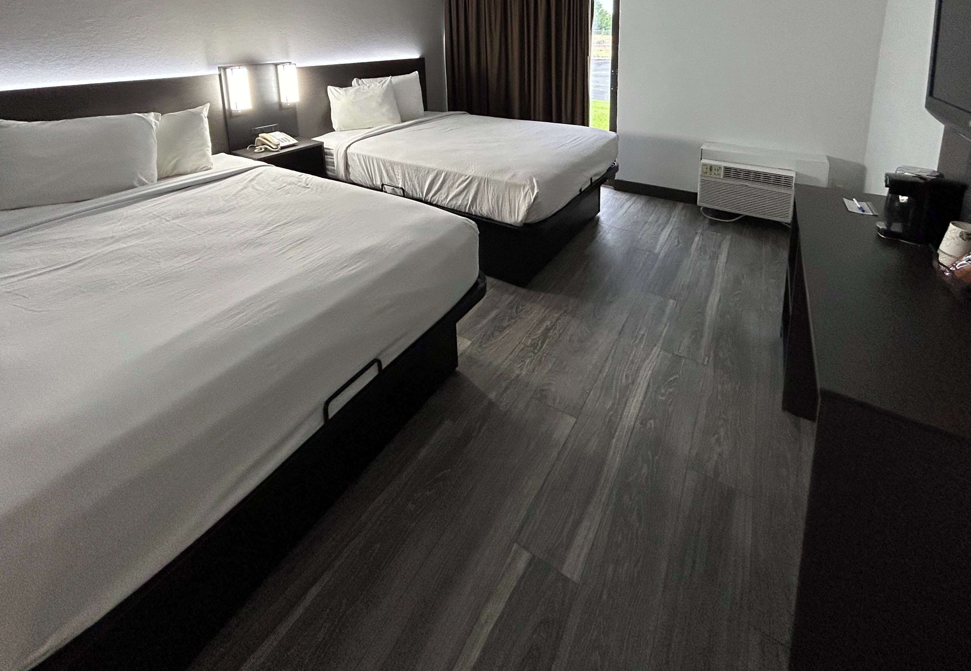 Une chambre d’hôtel avec deux lits, un bureau, un téléphone et une fenêtre avec des rideaux.