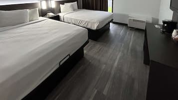 Une chambre d’hôtel avec deux lits, un bureau, un téléphone et une fenêtre avec des rideaux.