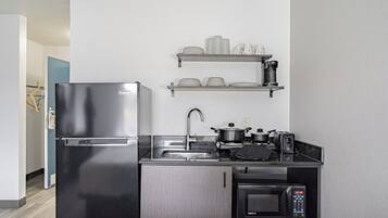 Una cocina compacta con refrigerador de acero inoxidable, microondas, tostadora y pileta.