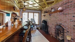Una cocina con barra de madera, chimenea de ladrillo y un ventanal amplio.