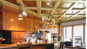 Una cocina con armarios de madera, una isla central con taburetes de bar, iluminación colgante y un amplio ventanal que proporciona luz natural.