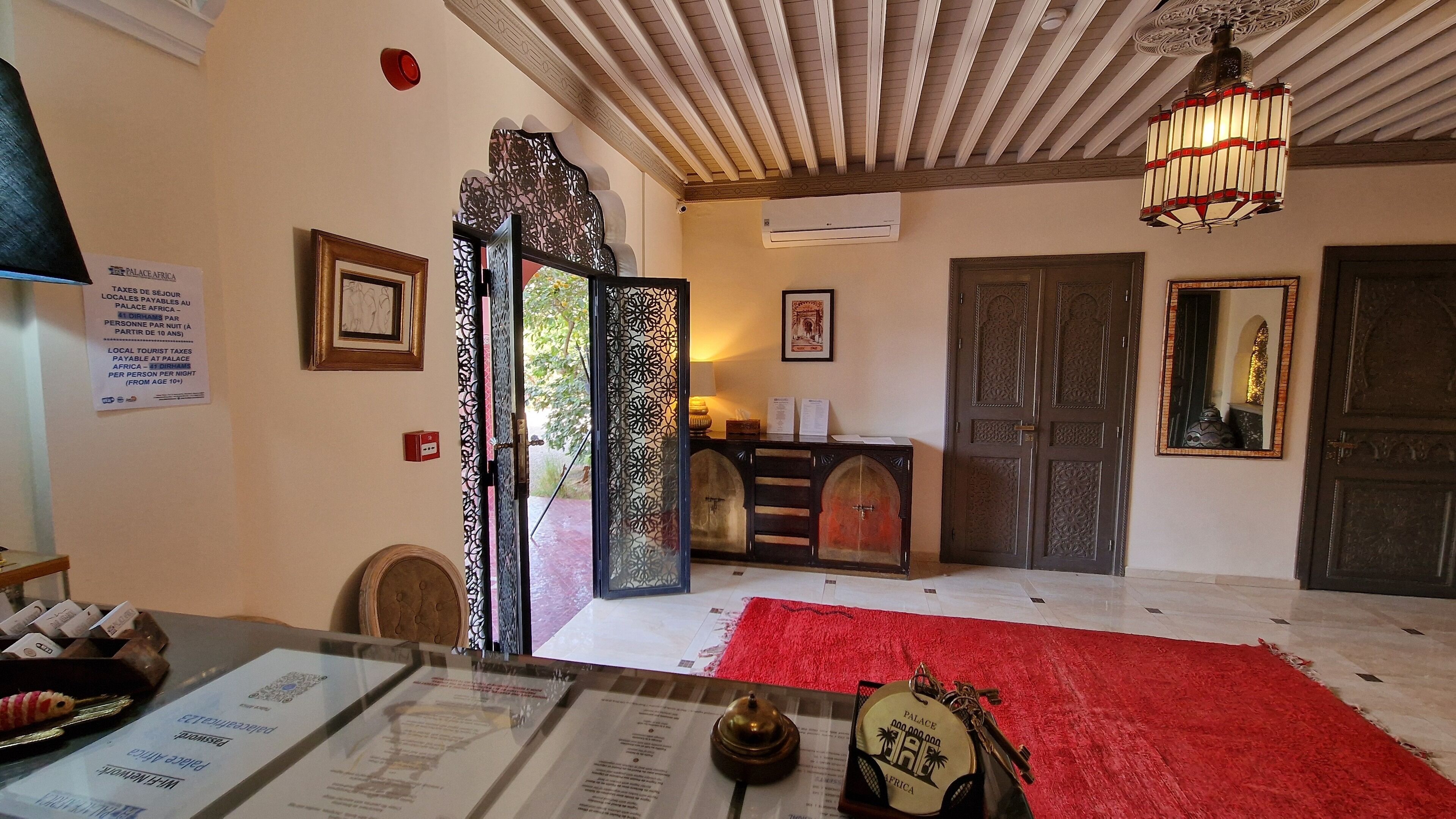 Un vestíbulo de hotel con alfombra roja, un candelabro y una recepción con un menú.