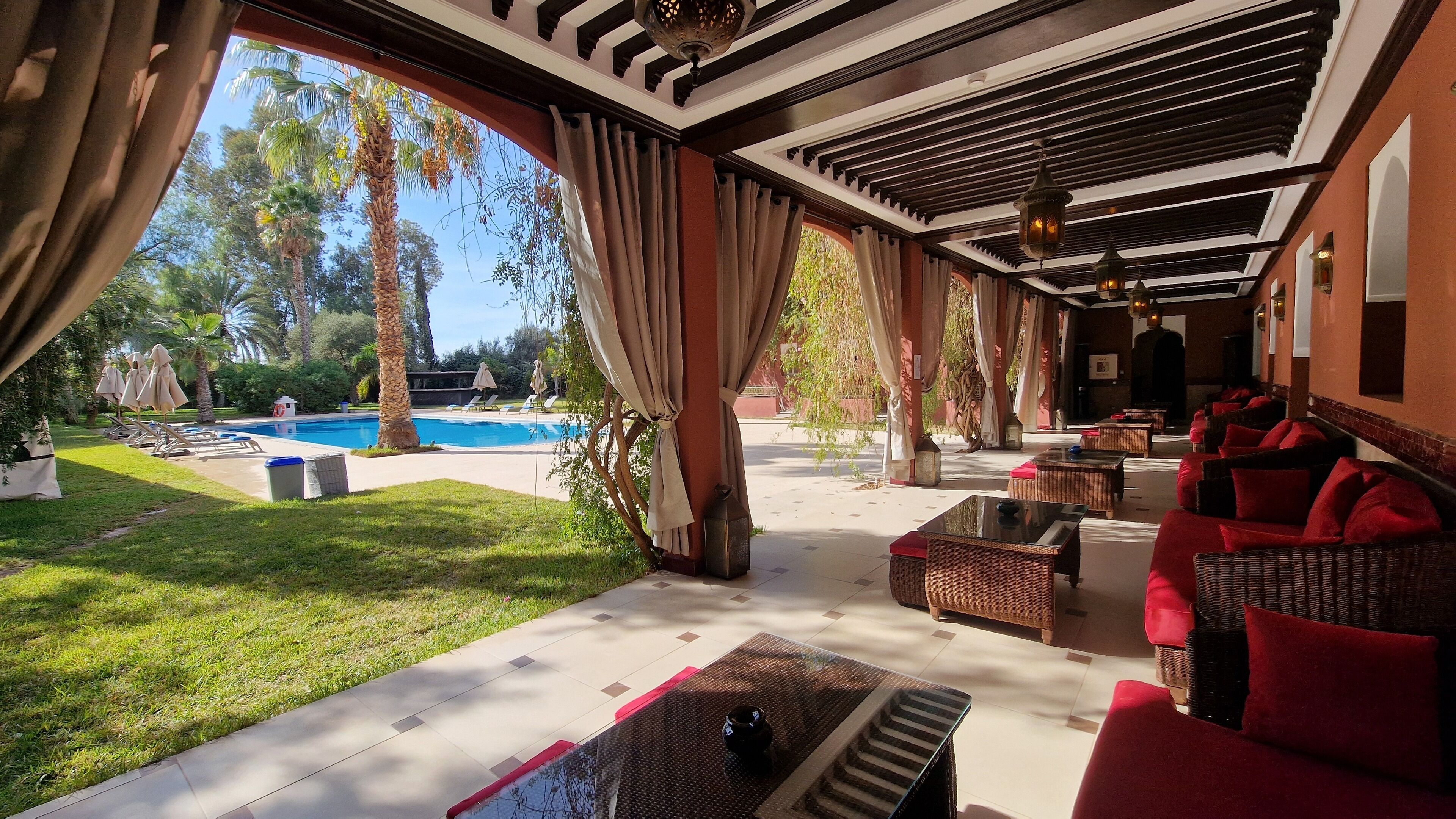 An outdoor patio area with a pool, wicker furniture, and a covered seating area.
