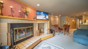 Ein Wohnzimmer mit Kamin, einem Essbereich und einer Küche im Hintergrund.