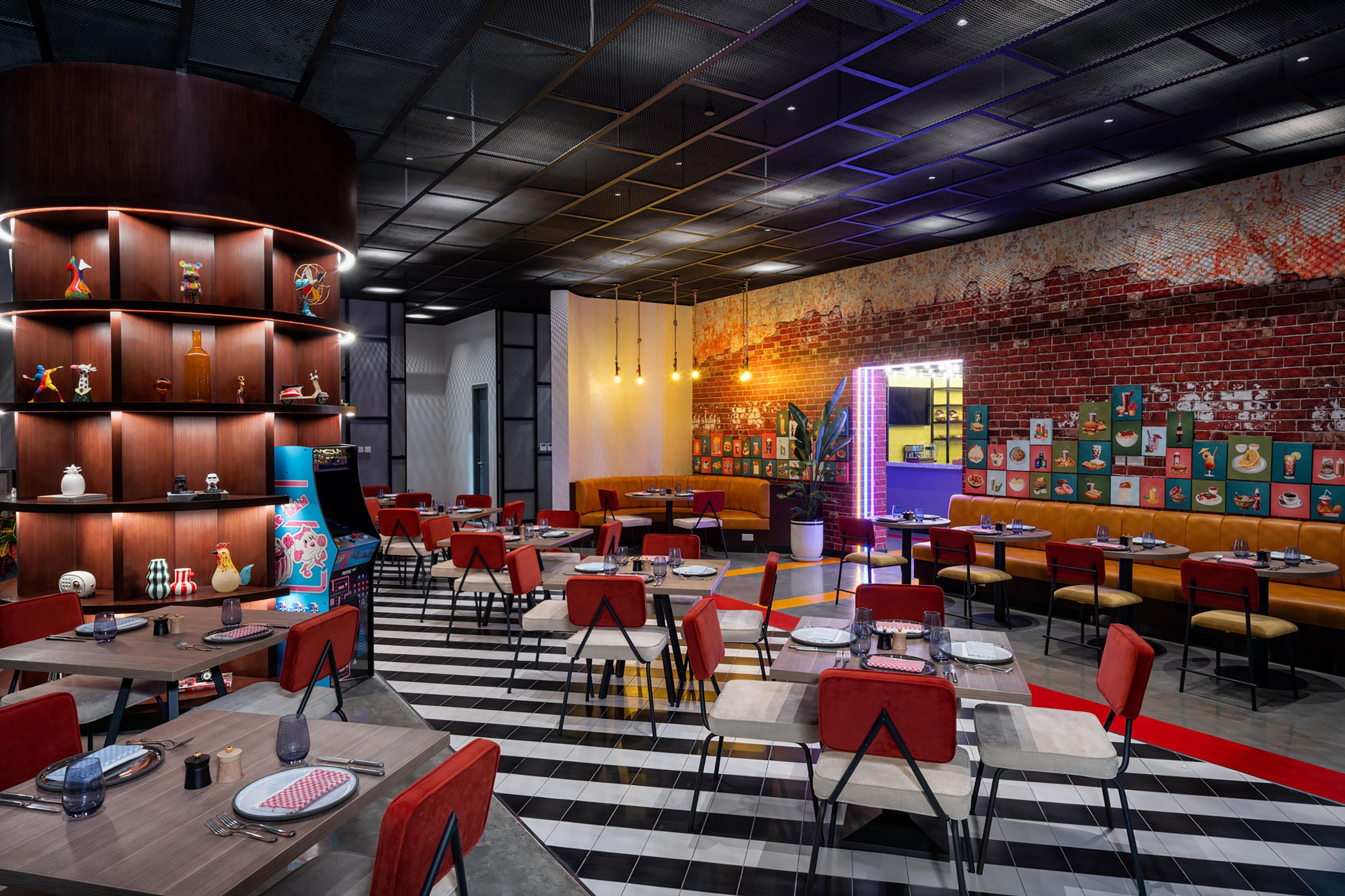 A modern restaurant interior with multiple dining areas, a brick wall mural, and a variety of seating options.