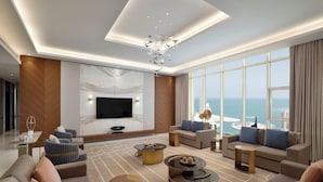 Een ruime woonkamer met een grote flatscreen televisie, comfortabele zitplaatsen en uitzicht op de oceaan.