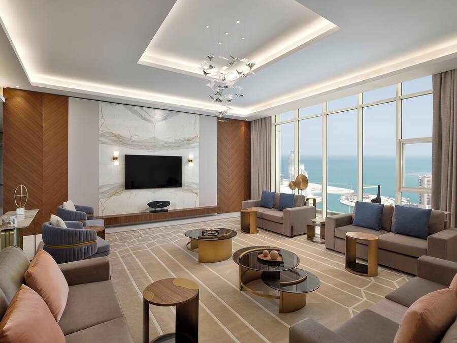 A spacious living room with a large flat-screen TV, comfortable seating, and a view of the ocean.