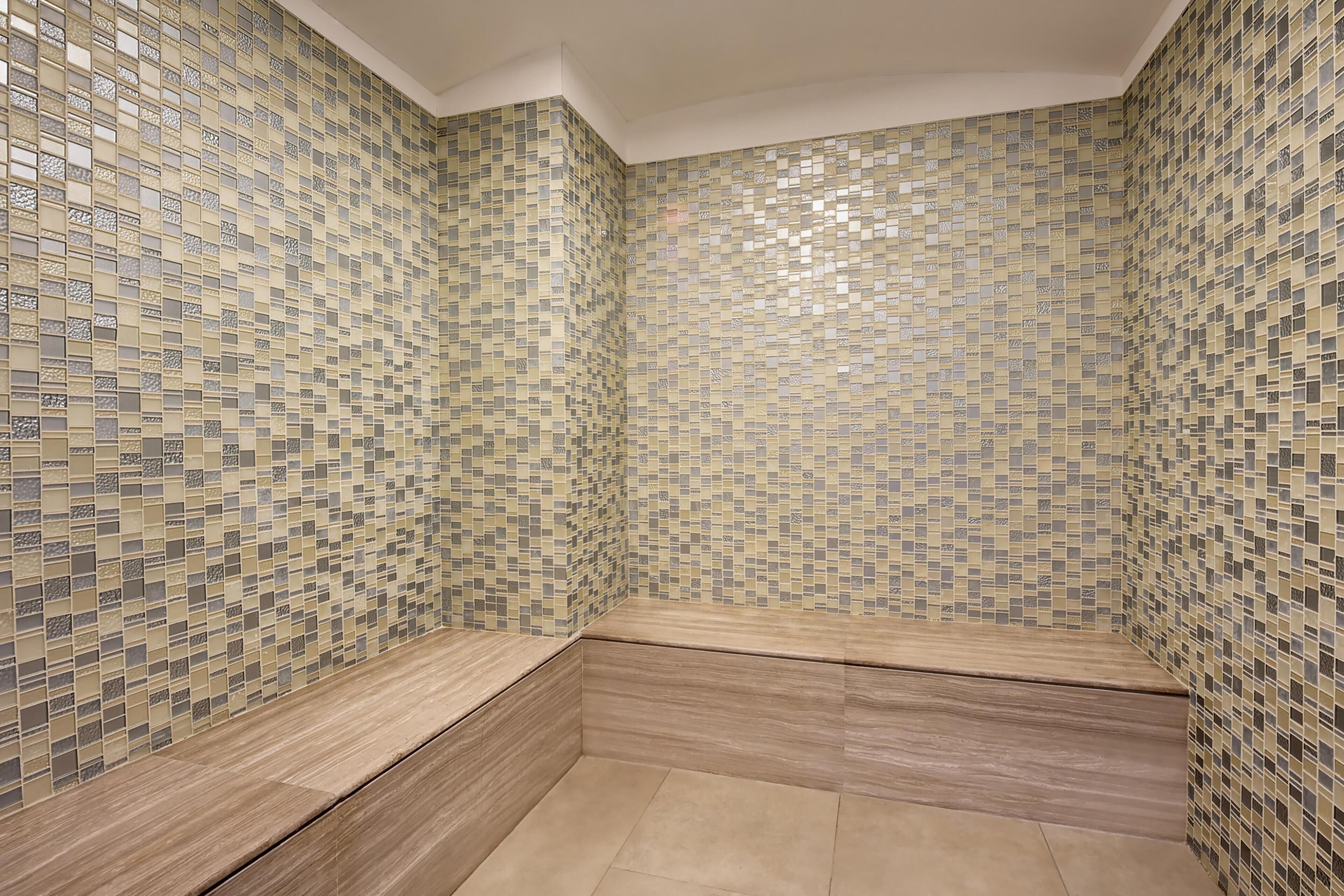 Ein Badezimmer mit Mosaikfliesen an den Wänden und einer hölzernen Sitzbank.