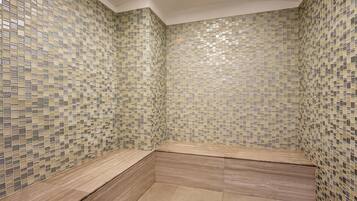 A bathroom with mosaic tile walls and a wooden bench.