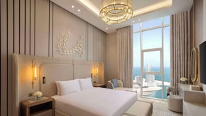 A modern hotel room with a large bed, a seating area, and a view of the city.