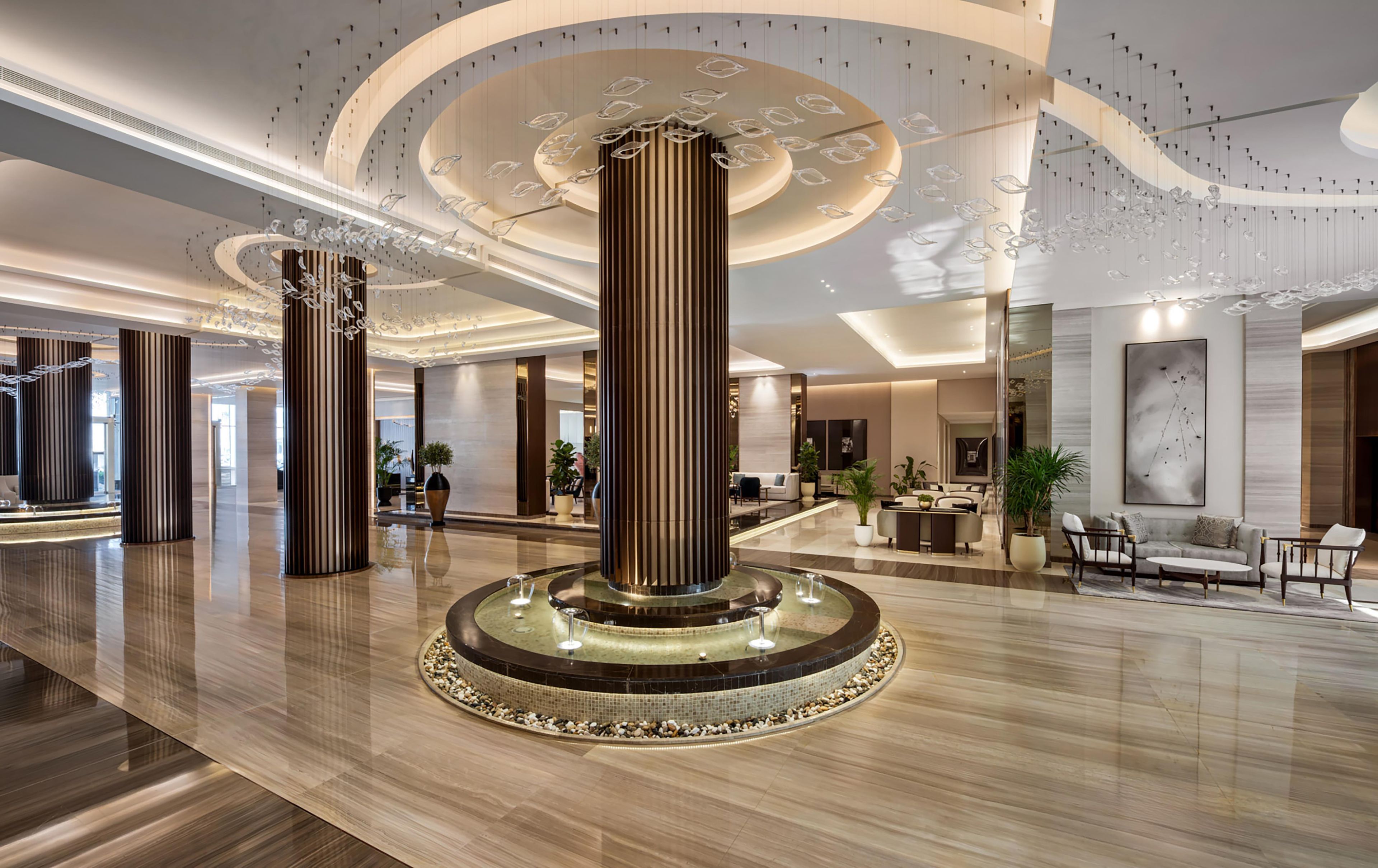 A spacious lobby with a central column, seating area, and a reception desk.