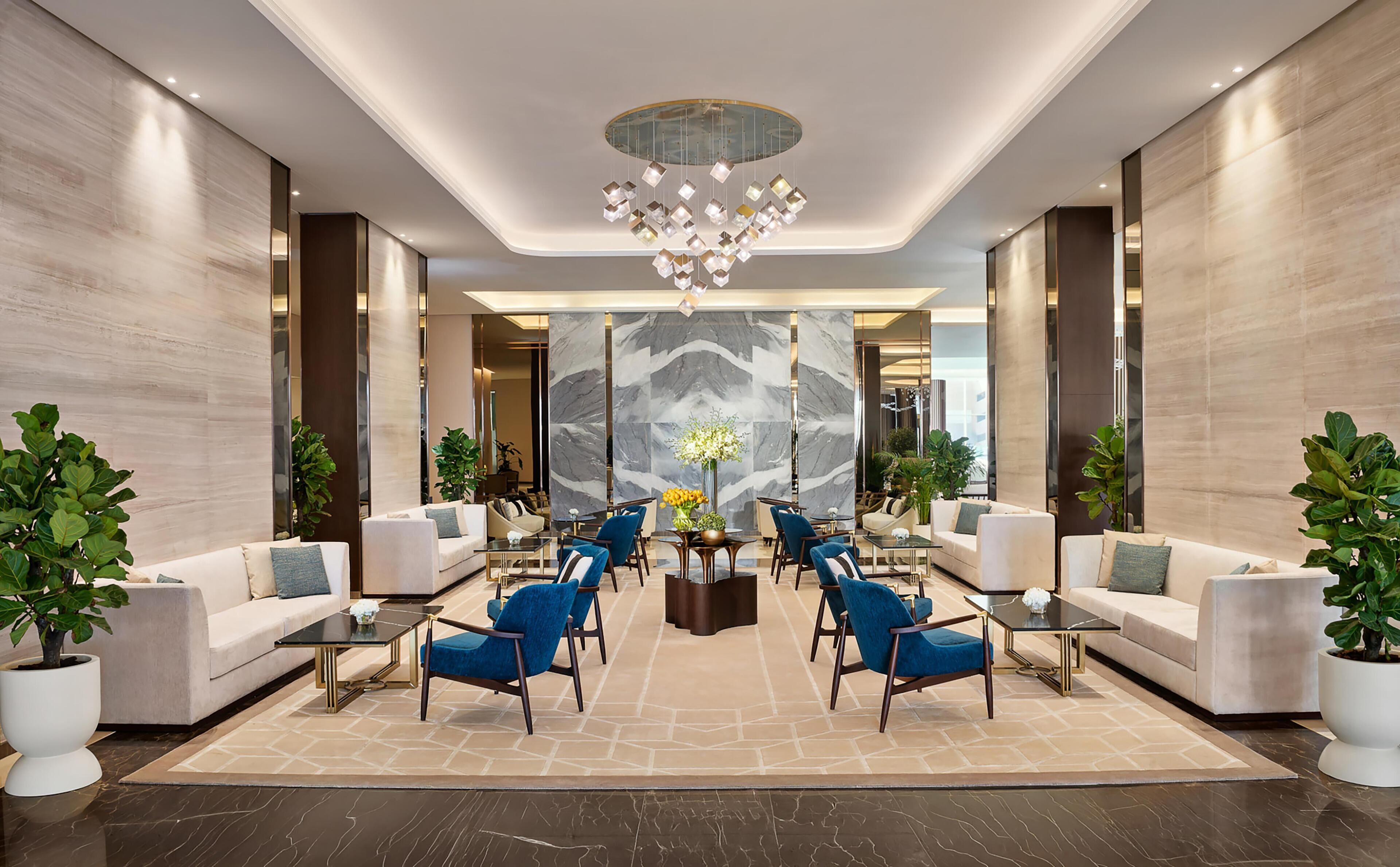A spacious lobby with a central seating area, a decorative chandelier, and a large mirror wall.