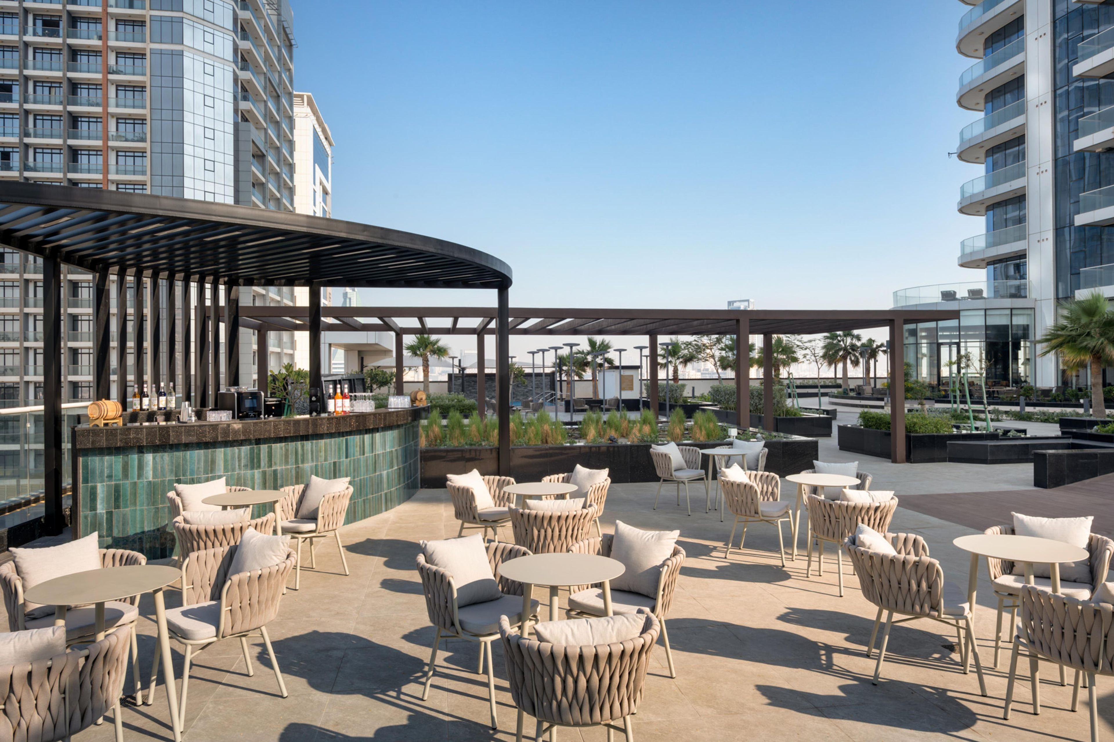Un espace extérieur aménagé avec des tables et des chaises rondes, un bar et une vue sur le paysage urbain.