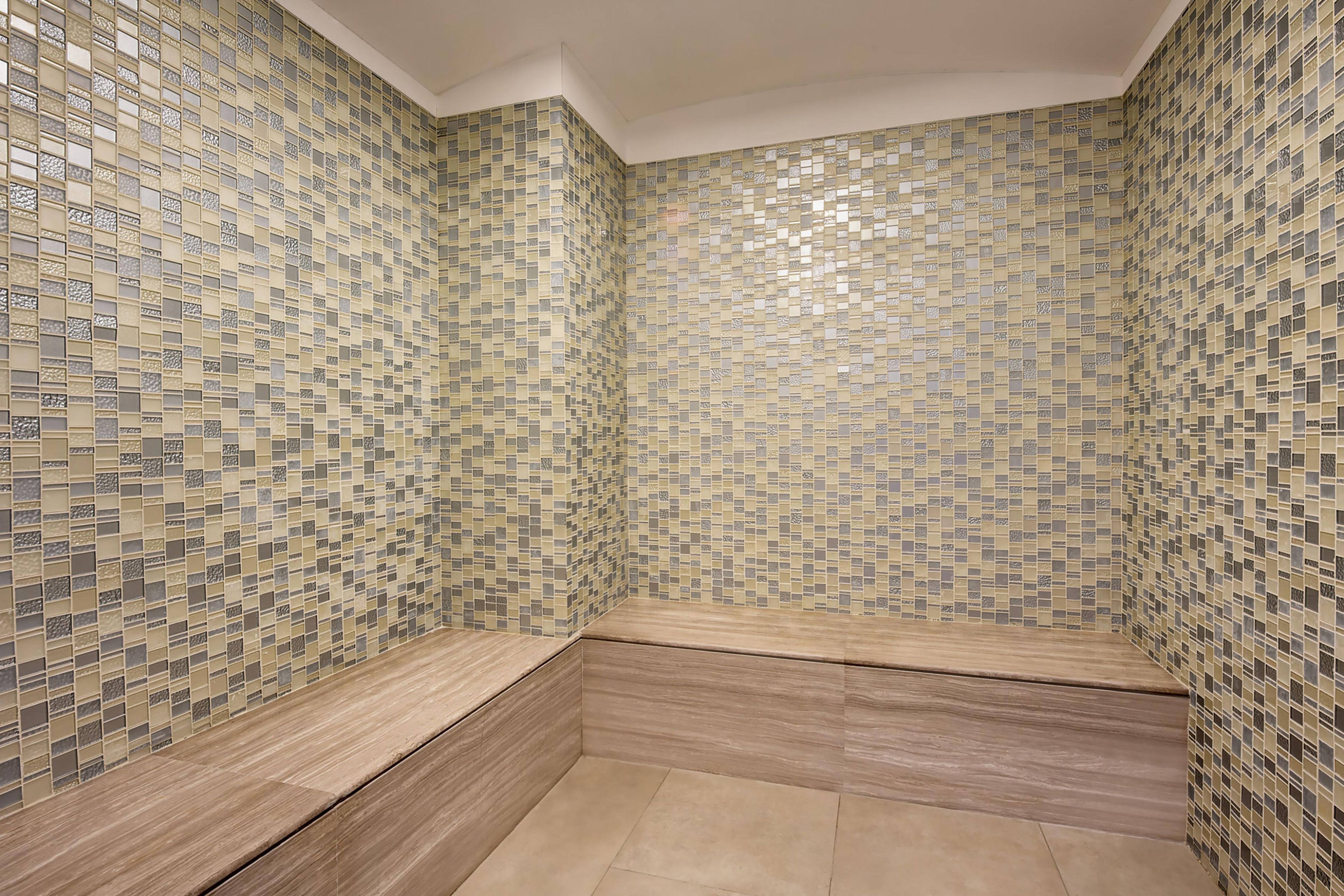 A bathroom with mosaic tile walls and wooden benches.