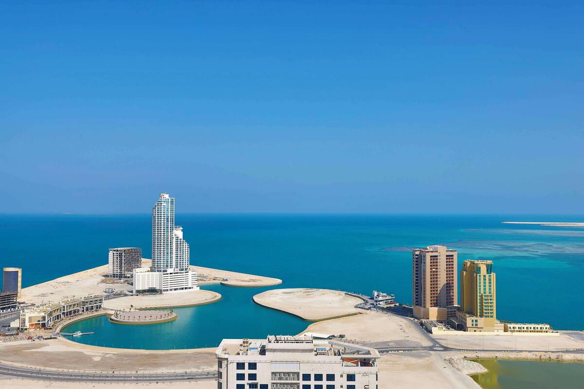 Un paisaje urbano costero con rascacielos, un puerto deportivo y una gran extensión de agua.