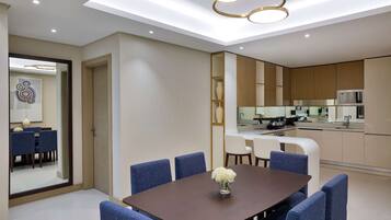 A modern dining area with a rectangular table, blue upholstered chairs, and a vase of flowers.